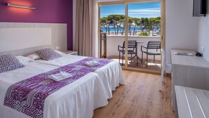 Une chambre d’hôtel avec deux lits, un balcon donnant sur la mer et un bureau.