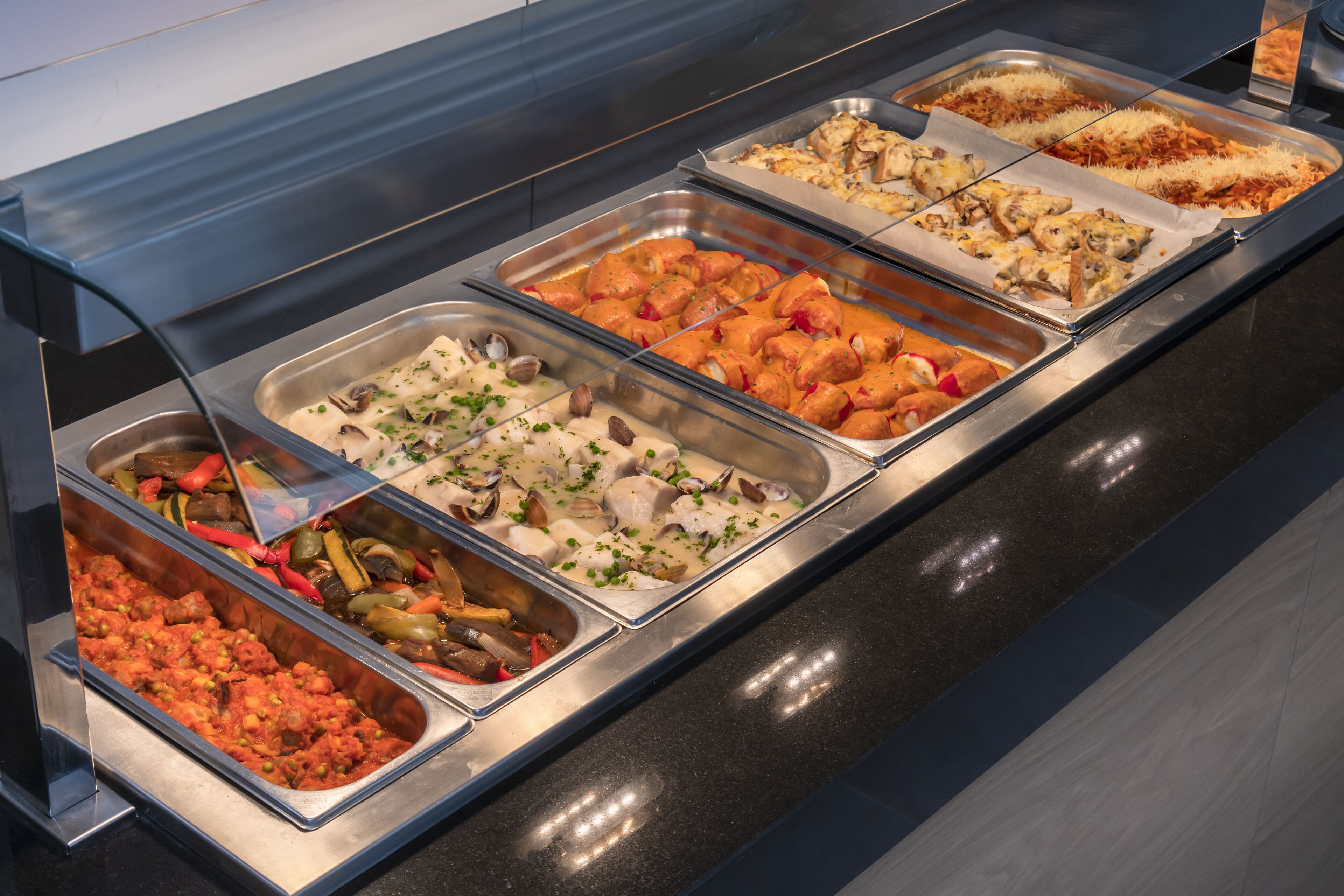 A buffet with various dishes including pasta, seafood, and salads.