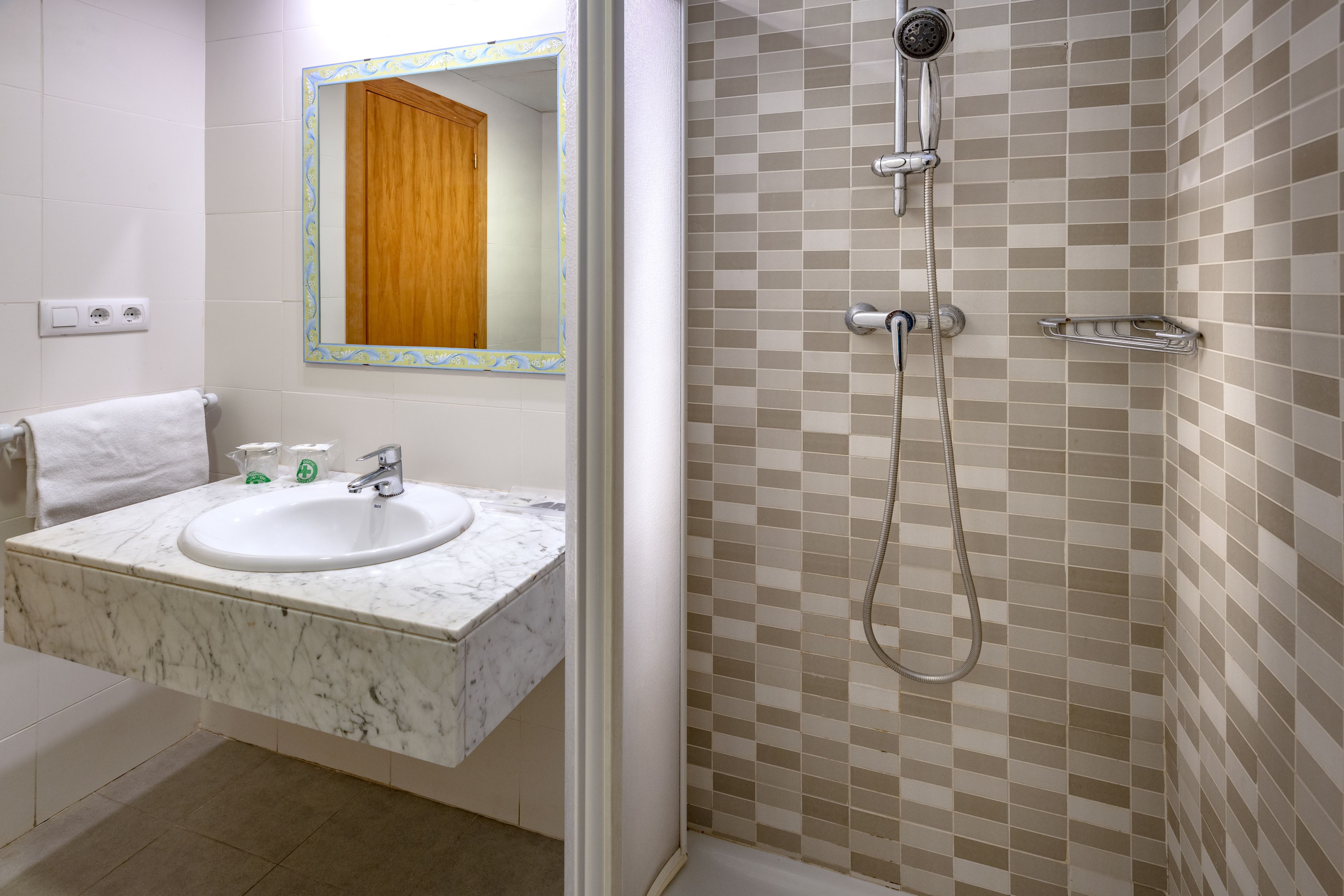 Un baño con lavamanos, espejo y ducha.