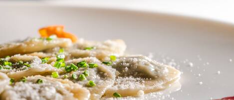 A plate of ravioli garnished with grated cheese and chopped green onions.