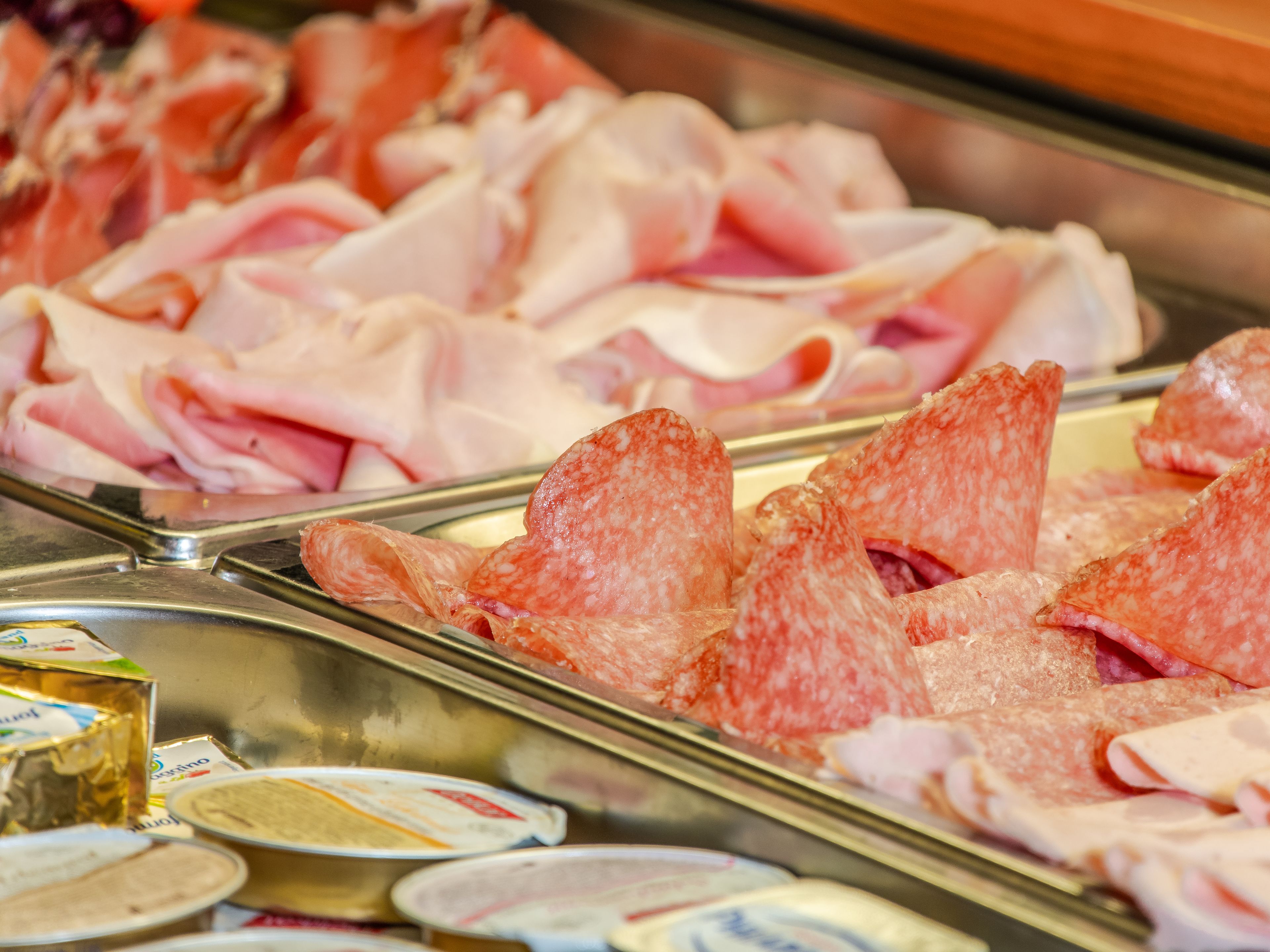 A variety of meats displayed in a deli counter.
