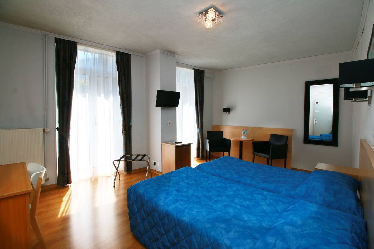 A hotel room with a large bed, a desk, a chair, and a TV.