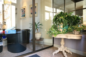 Un'area reception con una porta in vetro, una scrivania e diverse piante in vaso.