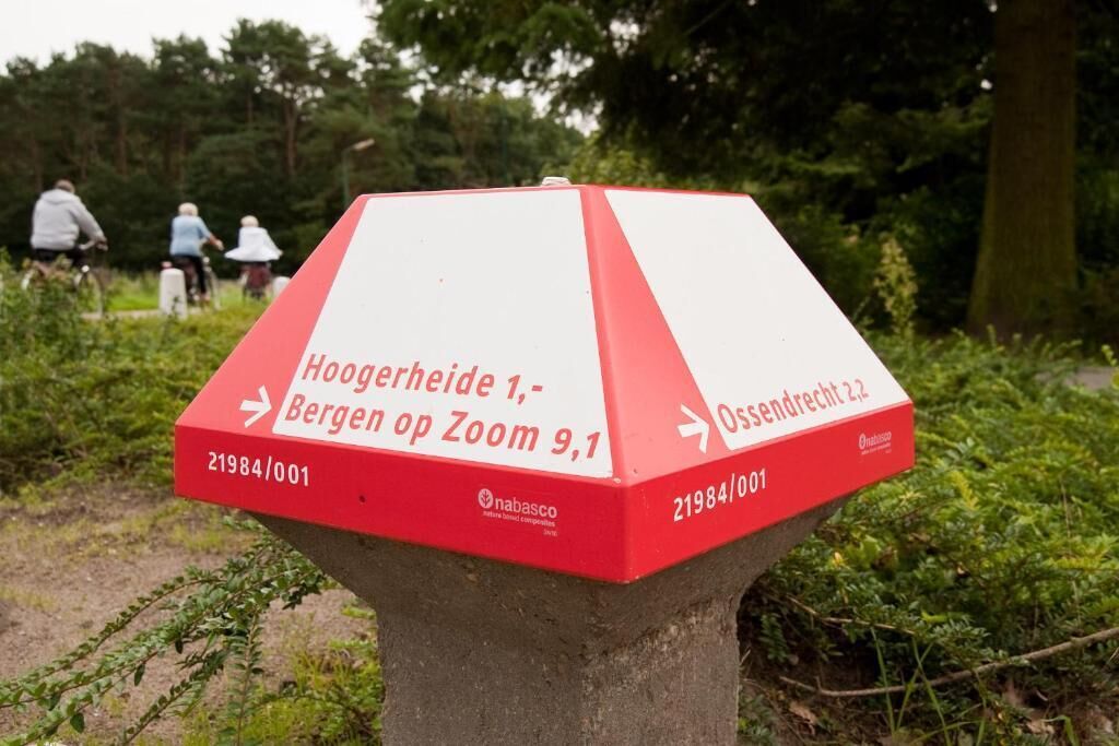 Una señal direccional roja y blanca con texto que indica Hoogerheide 1, Bergen op Zoom a 9,1 km y Ossendrecht a 2,2 km.