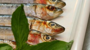 Une assiette de poisson grillé, garnie d’une feuille de basilic.