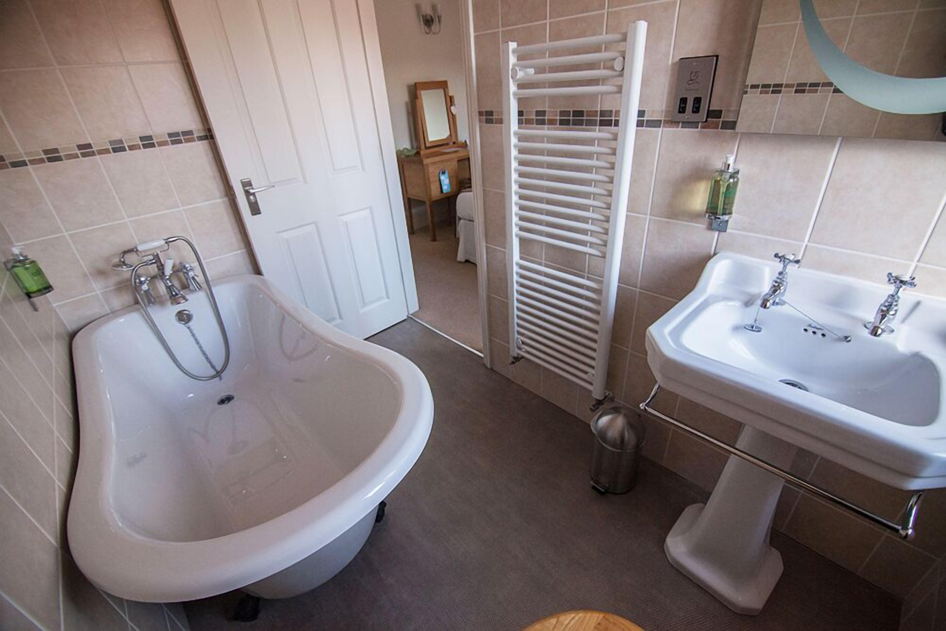 A bathroom with a bathtub, a sink, and a towel rack.