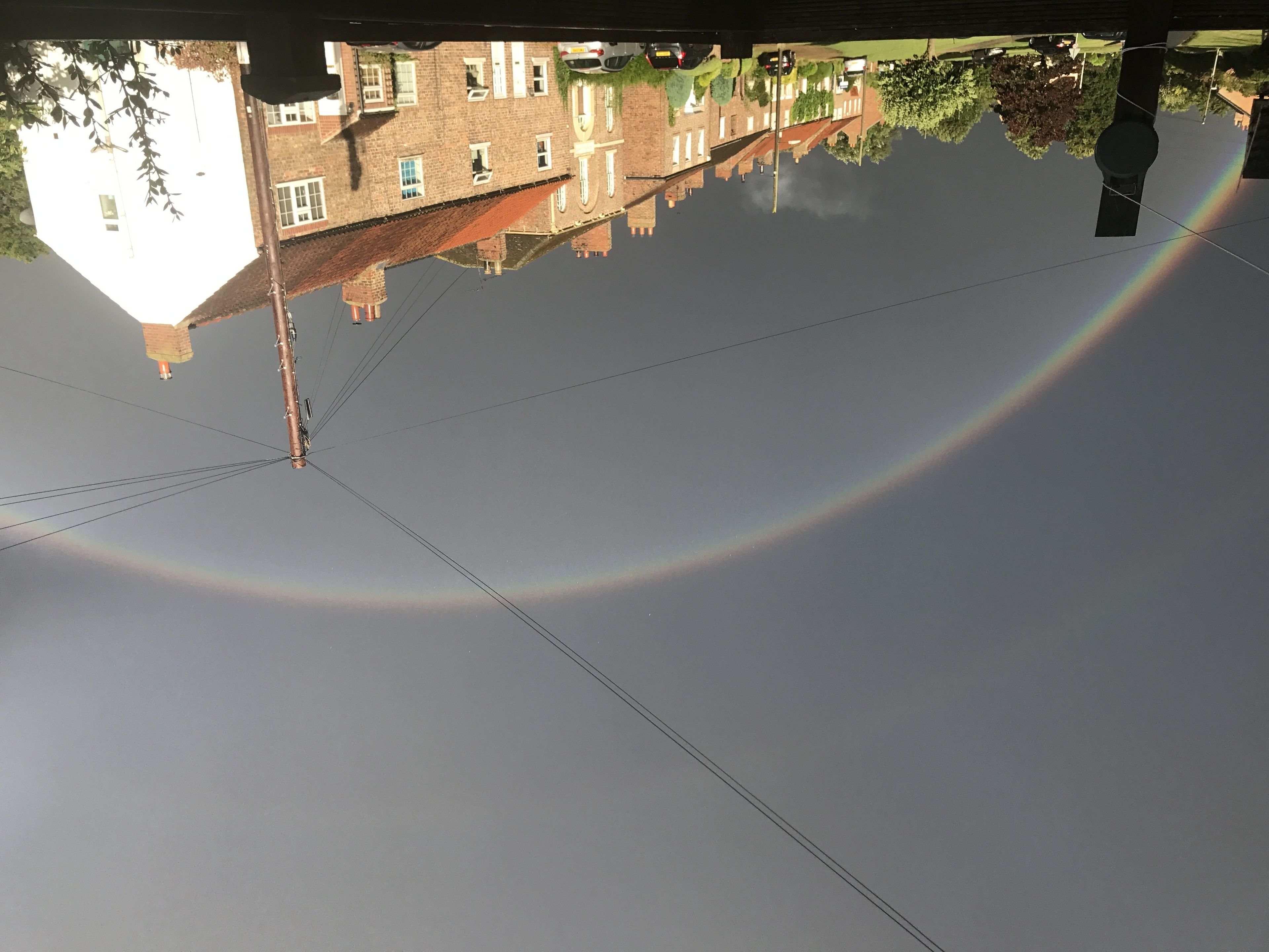 Le reflet d’un bâtiment et d’une rue se mire dans une étendue d’eau claire et calme.
