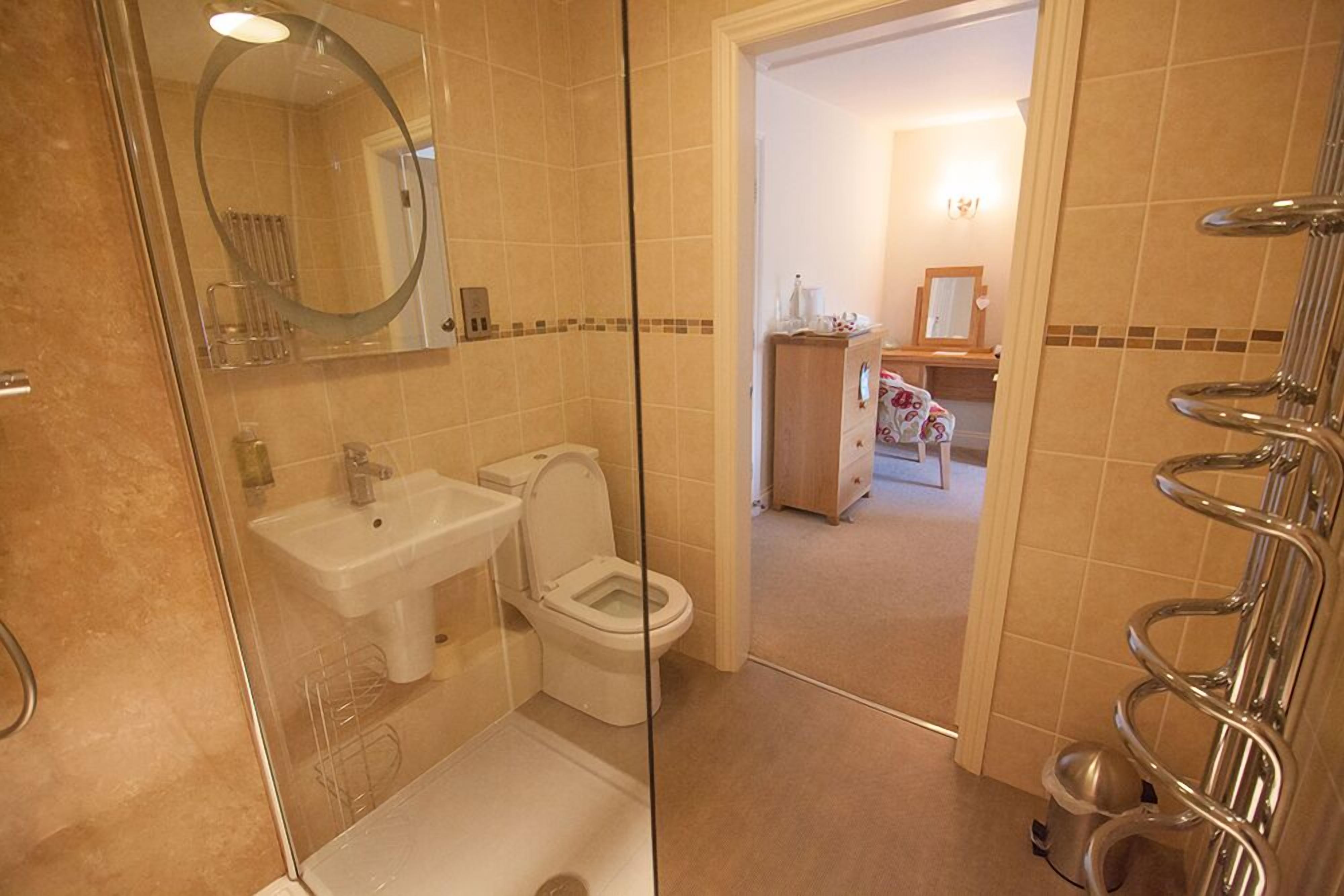 Een badkamer met een douche met glazen wand, een wastafel en een toilet.