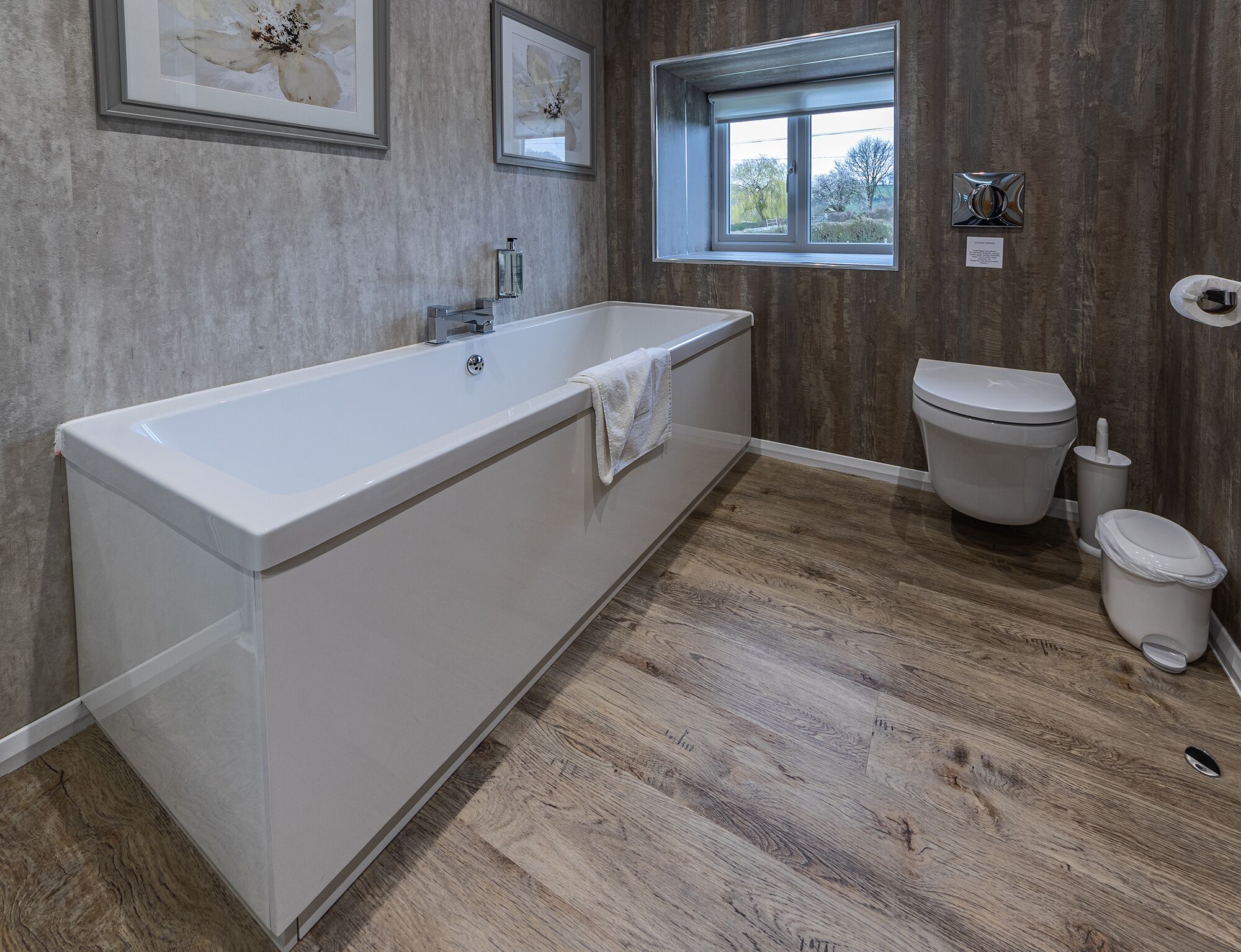 Un bagno moderno con una grande vasca, un water e una finestra vista alberi.