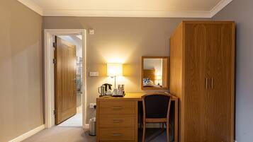 Ein Hotelzimmer mit einem Holztisch, einem Stuhl, einem großen Kleiderschrank und einem Spiegel.