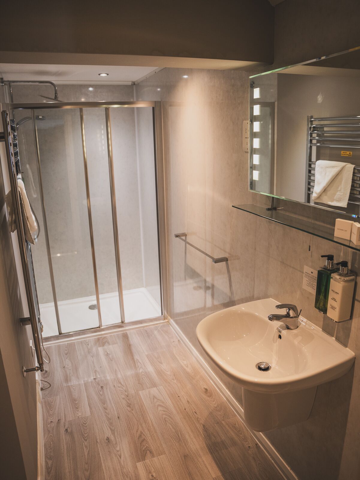 A modern bathroom with a glass shower enclosure, a large sink, and a mirror above it.