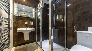 Un baño moderno con ducha de mampara de vidrio, lavamanos y retrete.