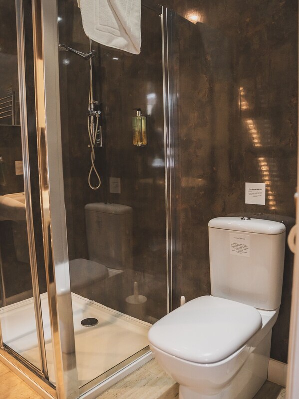 Une salle de bain moderne avec une douche à parois de verre, des toilettes et un petit lavabo.