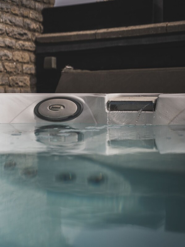 Un jacuzzi con panel de control y una pared de piedra al fondo.