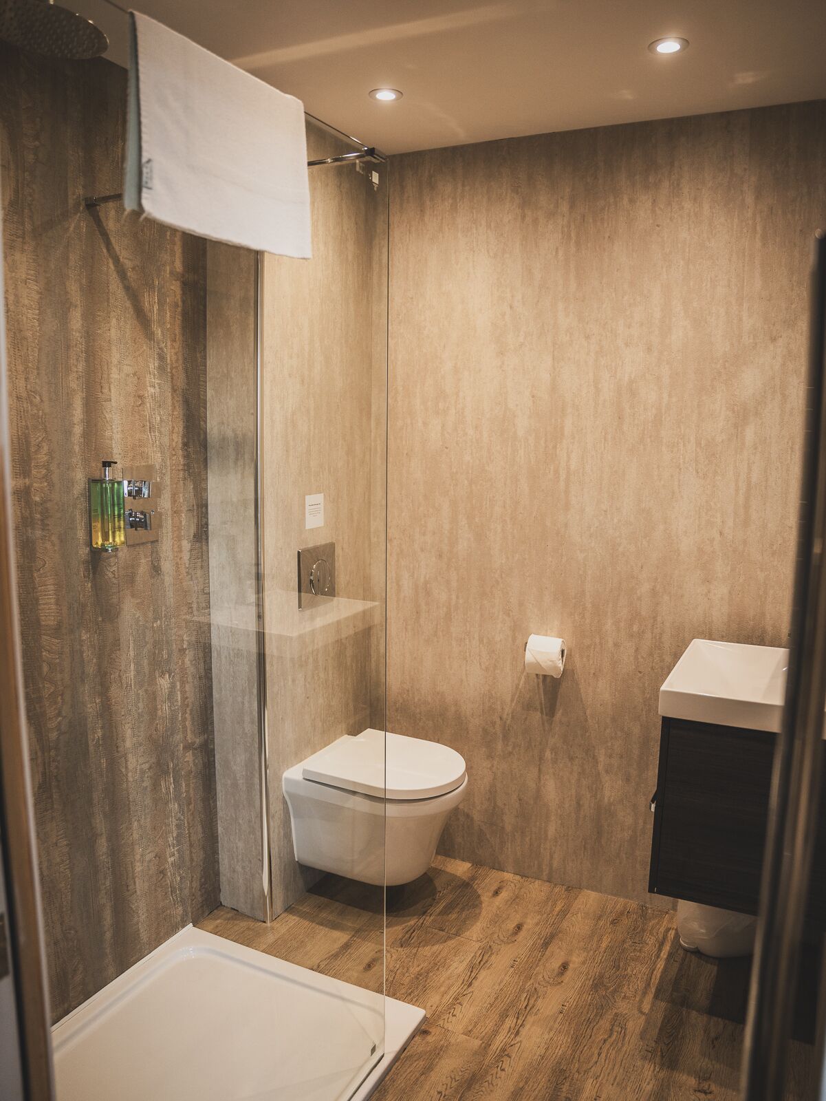 A modern bathroom with a glass-enclosed shower, a toilet, and a sink.