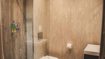 A modern bathroom with a glass-enclosed shower, a toilet, and a sink.