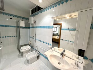 Family Room with Courtyard | Badkamer | Een douche, gratis toiletartikelen, een haardroger, een bidet
