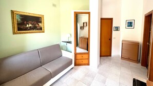 Een kamer met een bank, een spiegel, een kast en een deur.