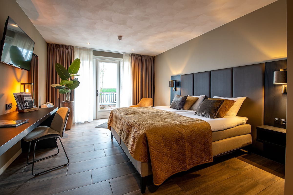 Une chambre d’hôtel moderne, dotée d’un grand lit, d’un bureau et d’une télévision.