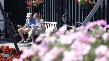 Un banc sur lequel sont assis deux personnes, un vélo et des jardinières.