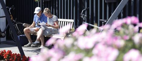 A bench with two people sitting, a bicycle, and flower planters.