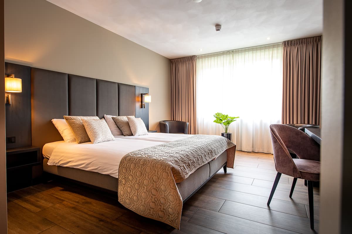 Une chambre d’hôtel moderne avec un grand lit, un bureau et une chaise.