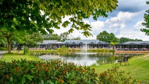 A hotel with a pond, covered outdoor seating, and a fountain. - Maashof (Venlo)