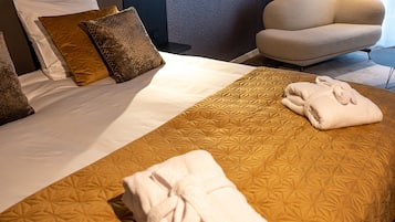 Een net opgemaakt bed met een beddekleed met patroon, twee kussens en een opgevouwen handdoek aan de zijkant.