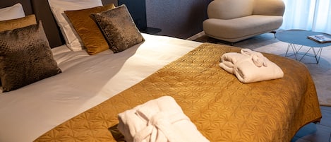 A neatly made bed with a patterned bedspread, two pillows, and a folded towel on the side.
