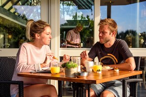 Una pareja cenando en una mesa de madera con vistas al exterior.