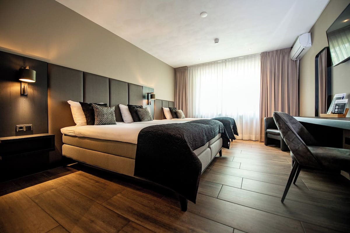Une chambre d’hôtel moderne avec un grand lit, des tables de chevet, un bureau et une chaise.