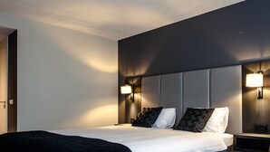 Una habitación de hotel con una cama grande, dos lámparas de noche, una mesita de noche y una silla.