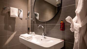 A modern bathroom with a white sink, a mirror, and a towel rack.