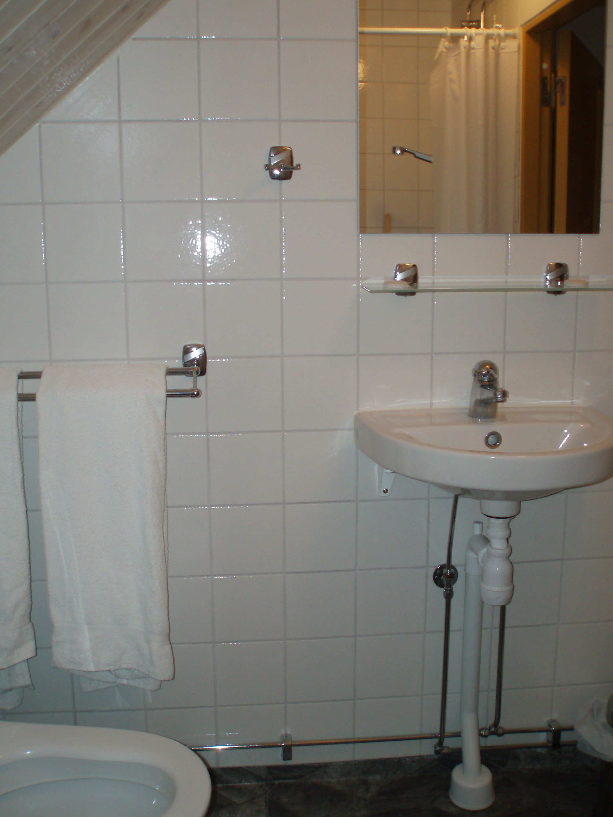 Un baño con lavamanos blanco, espejo e inodoro.