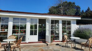 Une véranda avec des portes vitrées, un sol en pierre et des meubles en osier.