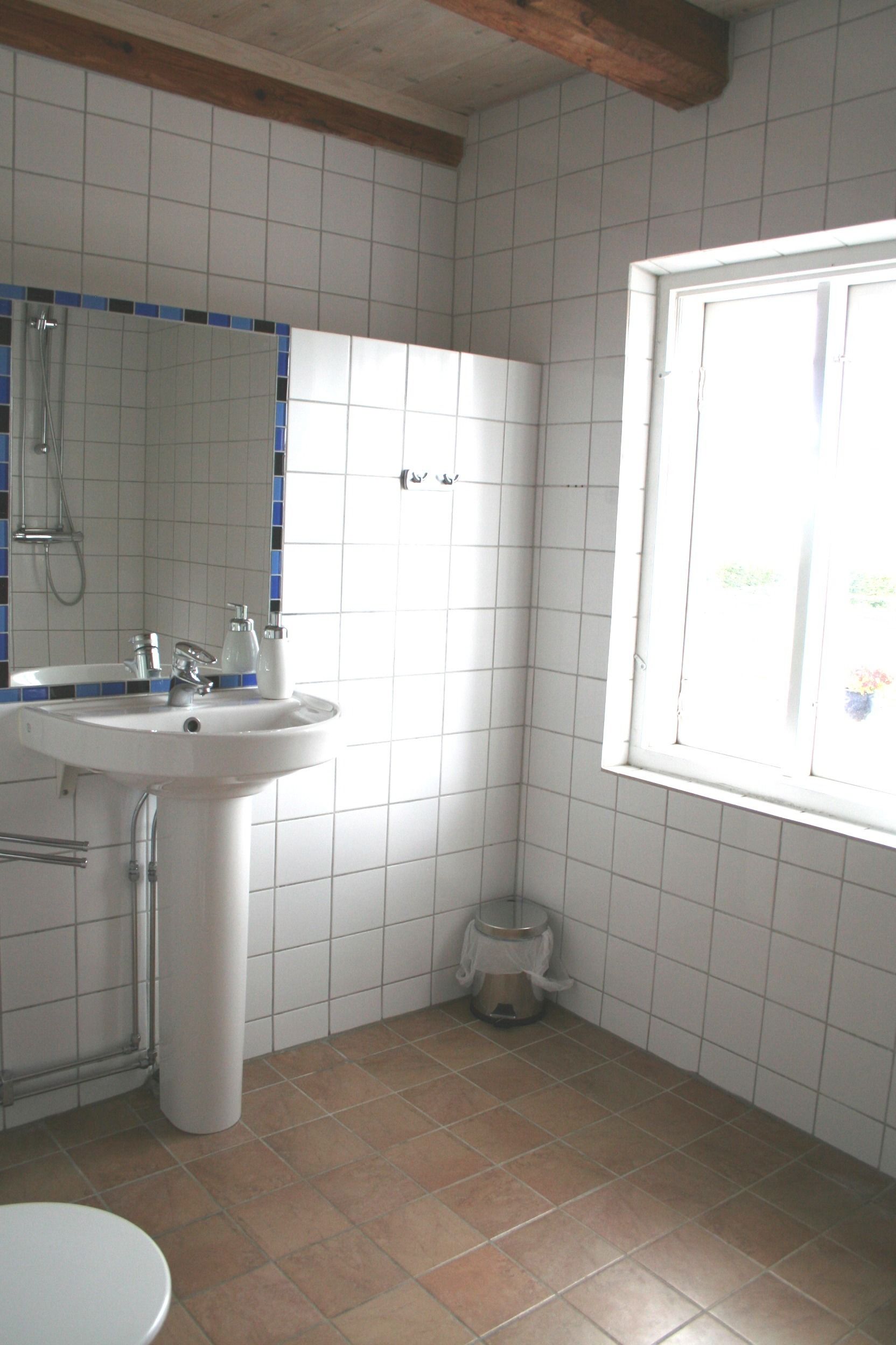 A bathroom with a sink, mirror, and window.