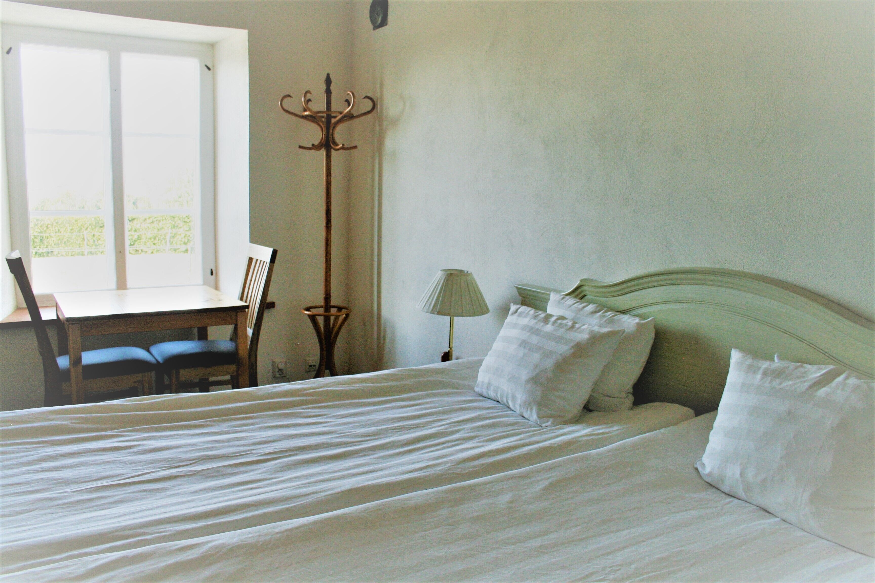 Un dormitorio con cama, escritorio, silla y lámpara de pie.