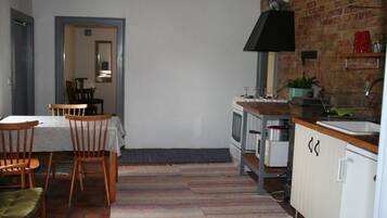 A compact kitchen with a stove, sink, and cabinets. There is a dining area with chairs and a table.