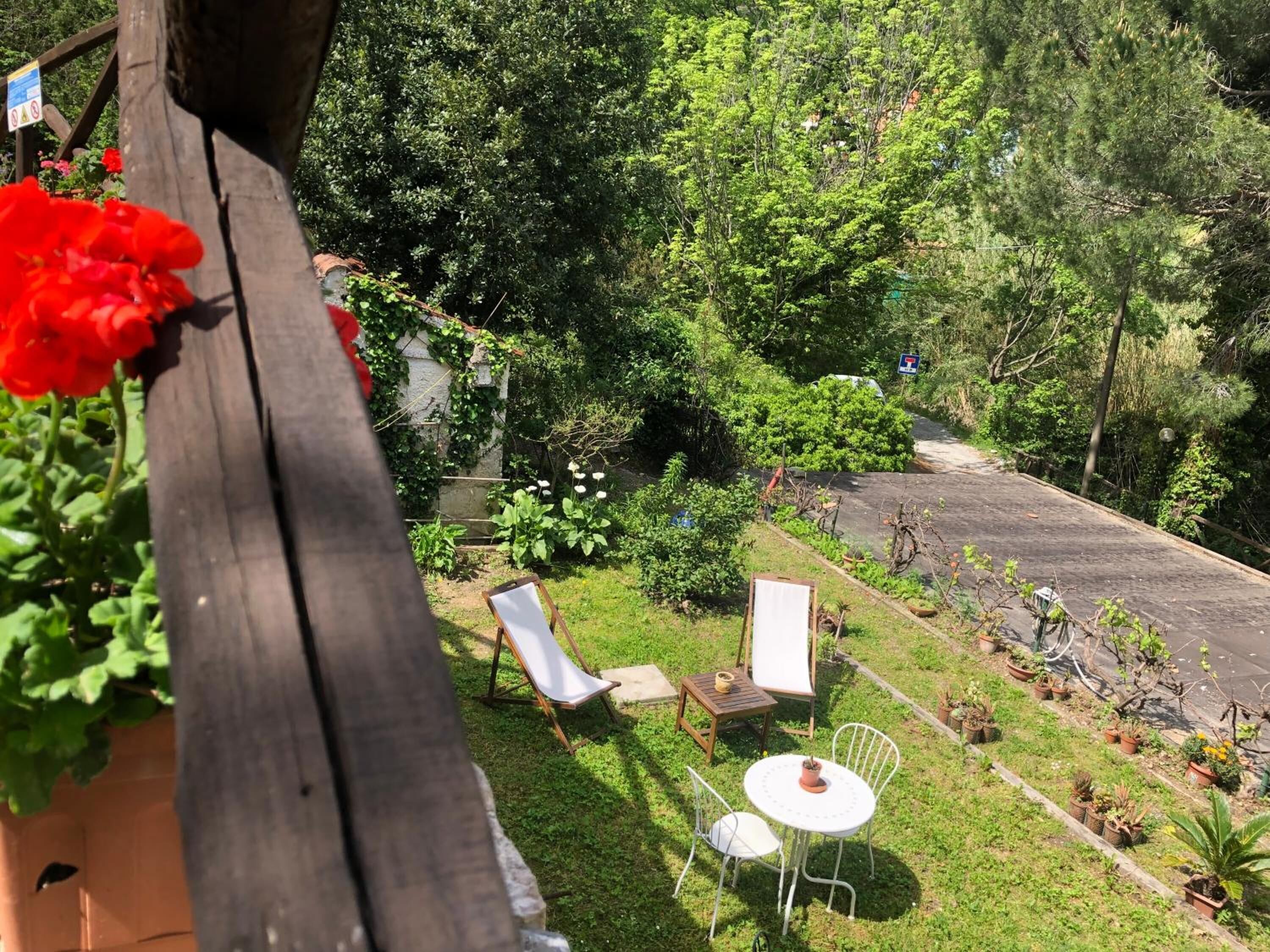 A garden area with a wooden fence, a small table with chairs, and potted plants.