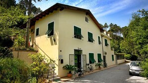 A two-story building with a yellow facade, green shutters, and a staircase leading to the entrance. - Casale Coreallo (Spotorno)
