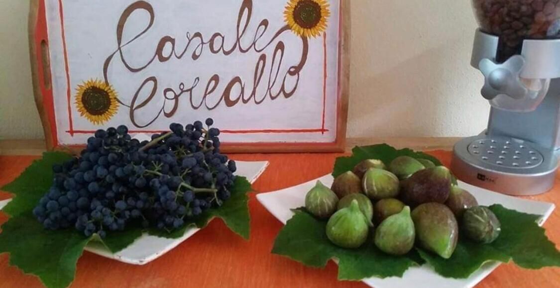A table with a sign reading "Carale Cerealio" and two plates of grapes and figs.
