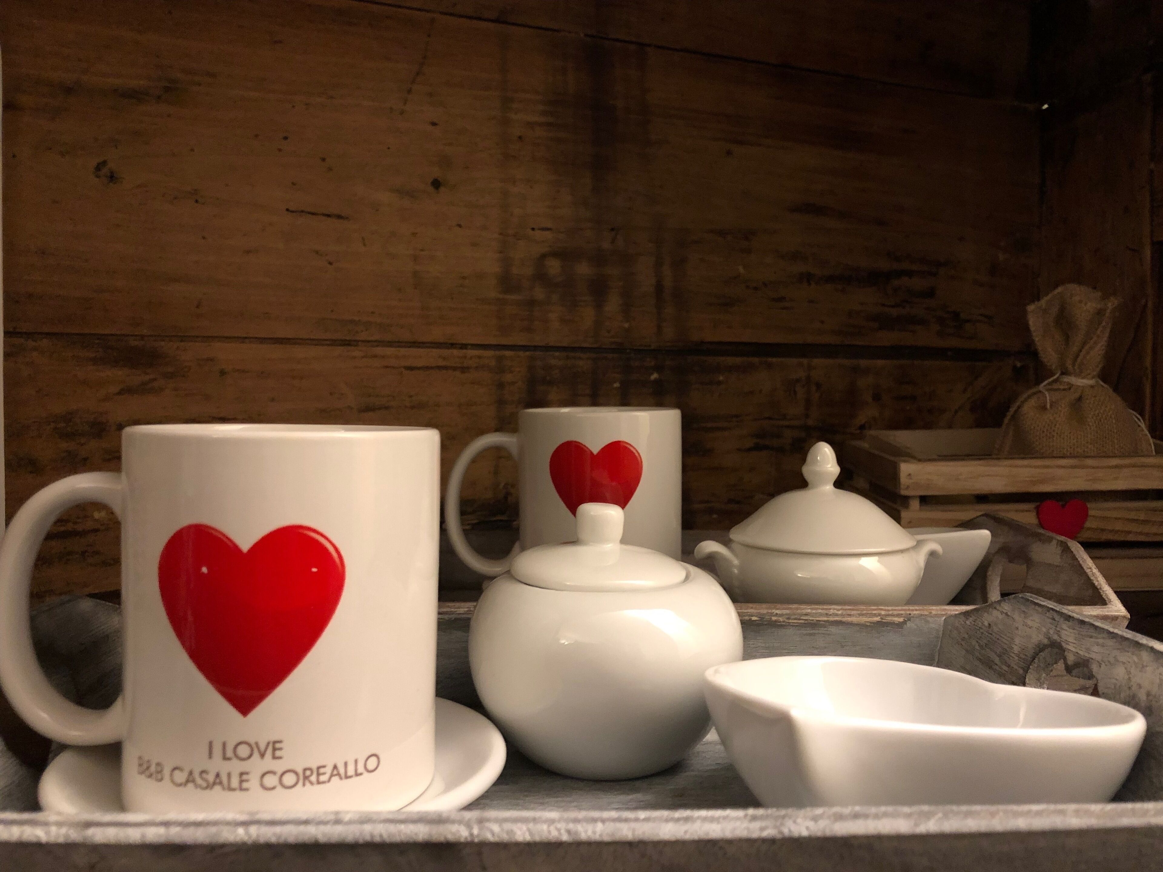 Un juego de té de cerámica blanca que incluye una tetera, tazas y un azucarero, con un diseño de corazón en las tazas.