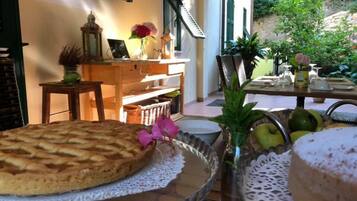 A dining table with a cake, a glass vase with flowers, and a fruit bowl.