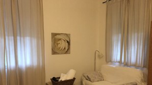 A room with a white sofa, a small table with a basket, a lamp, and a framed picture on the wall. - Casale Coreallo (Spotorno)