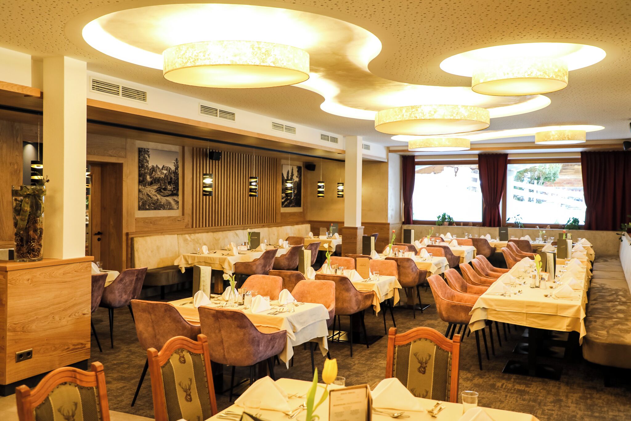 Ein Restaurant mit mehreren Tischen, Stühlen und hängenden Lampen.