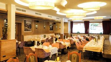 Ein Restaurant mit mehreren Tischen, Stühlen und hängenden Lampen.