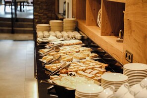 A buffet with various food items and stacked plates.