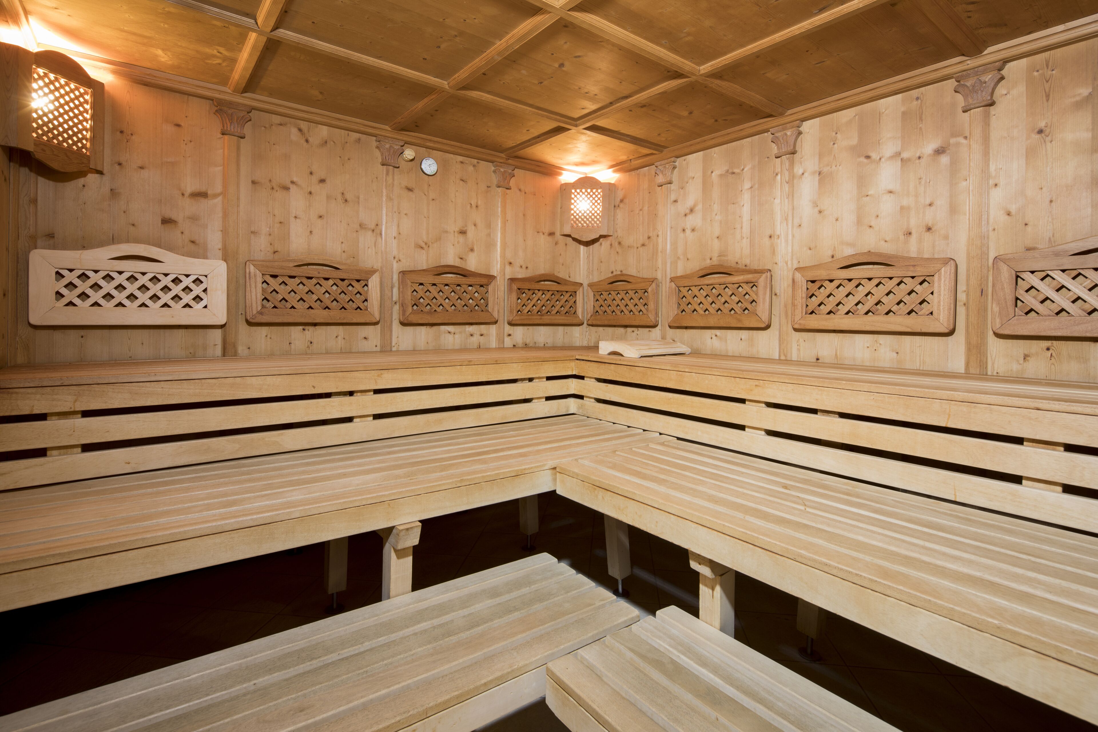 A sauna with wooden benches and lattice-patterned wall panels.