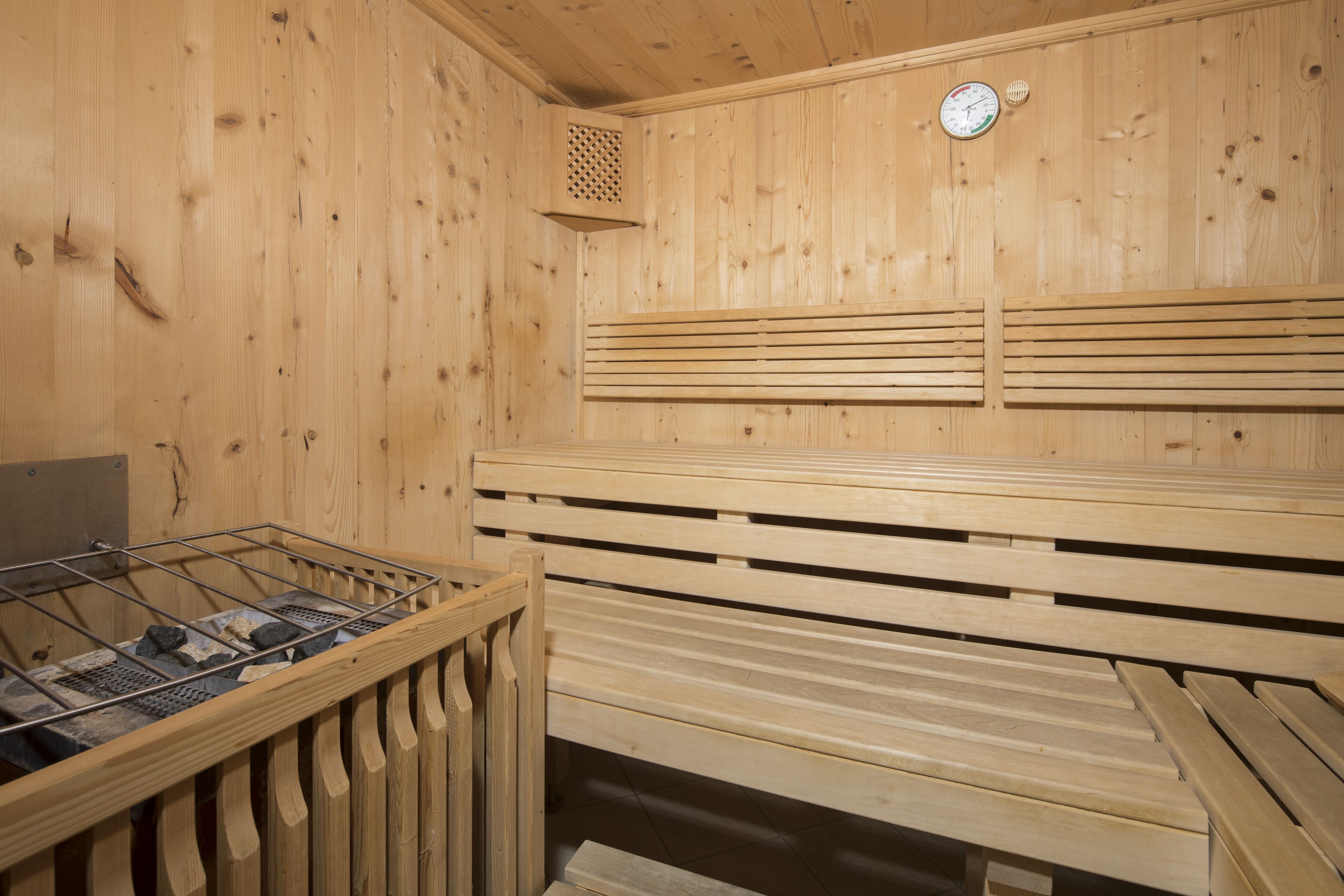 A sauna with wooden benches, a ventilation system, and a clock on the wall.