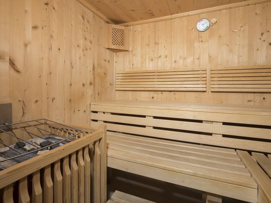 A sauna with wooden benches, a ventilation system, and a clock on the wall.